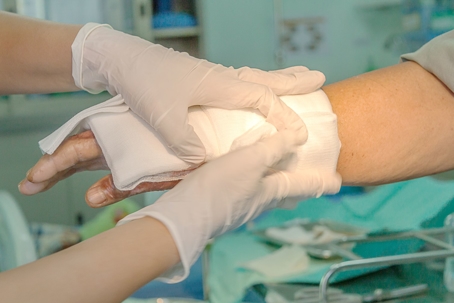 nurse treating wound on hand